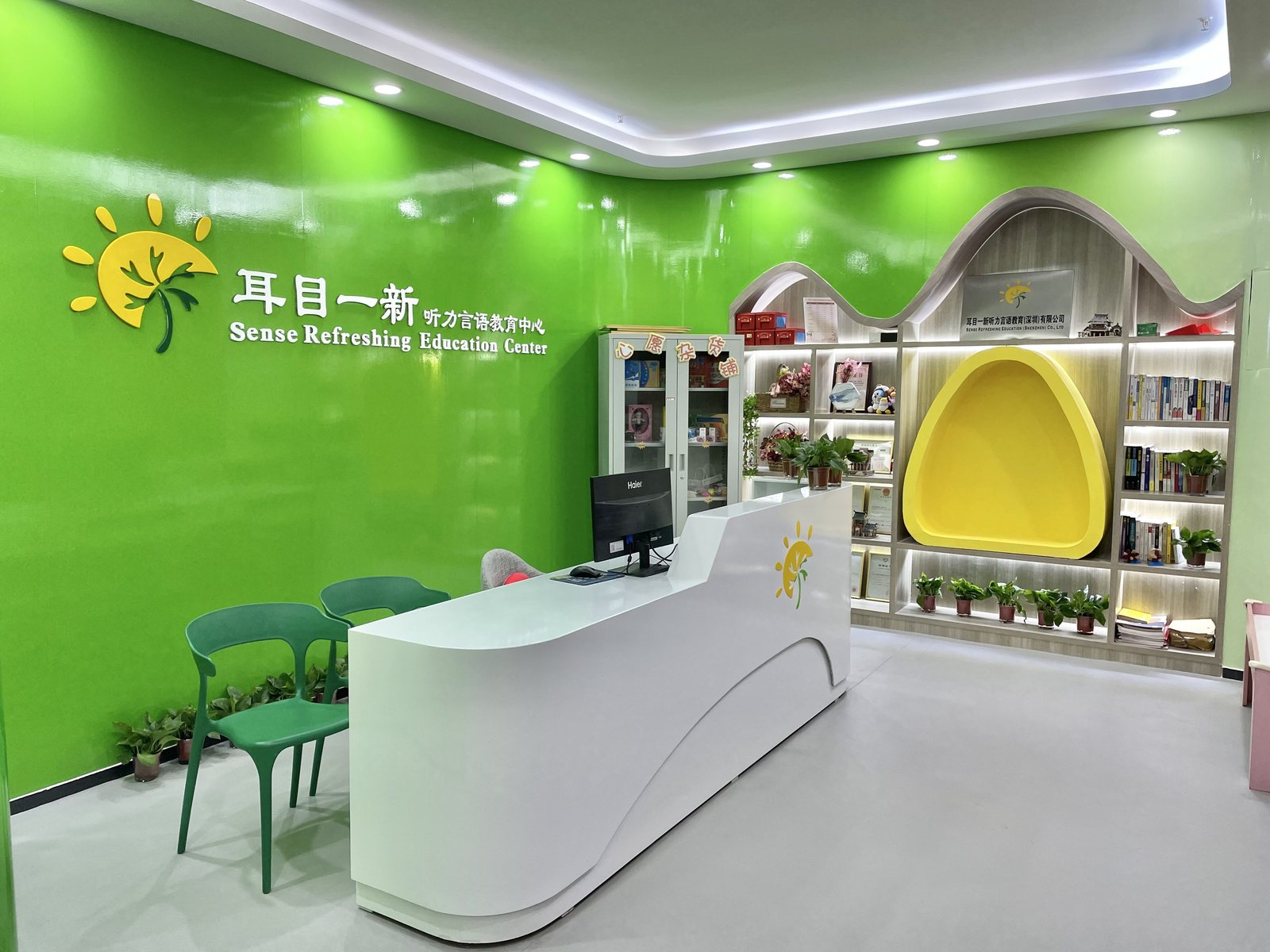 耳目一新康复教育中心前台，绿色墙面与白色接待台